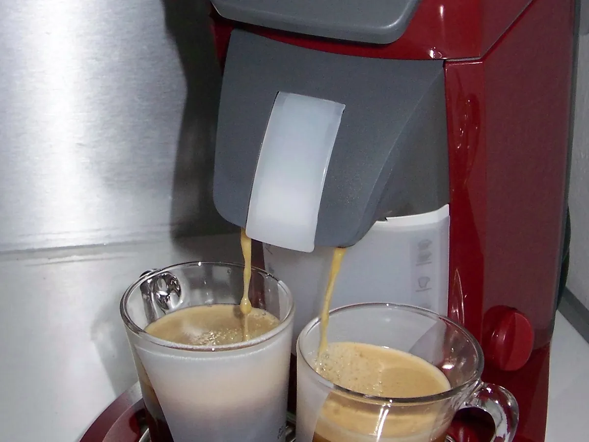 Single-serve pod coffee machine pouring a cup on a counter